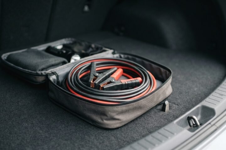 Jumper cables coiled inside a vehicle trunk emergency kit.